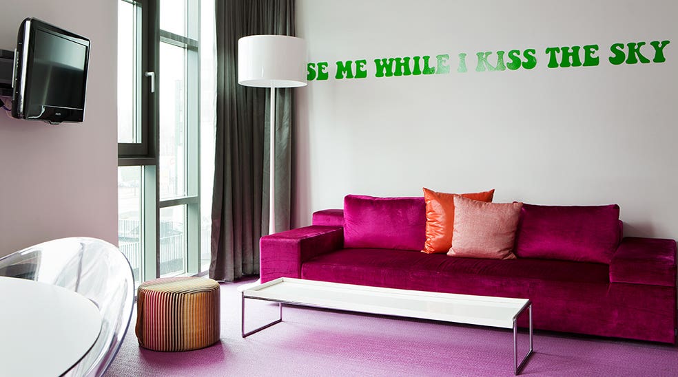 Suite Flowerpower rosa sofa og grøn tekst på væggen ved Comfort Hotel Union Brygge Drammen