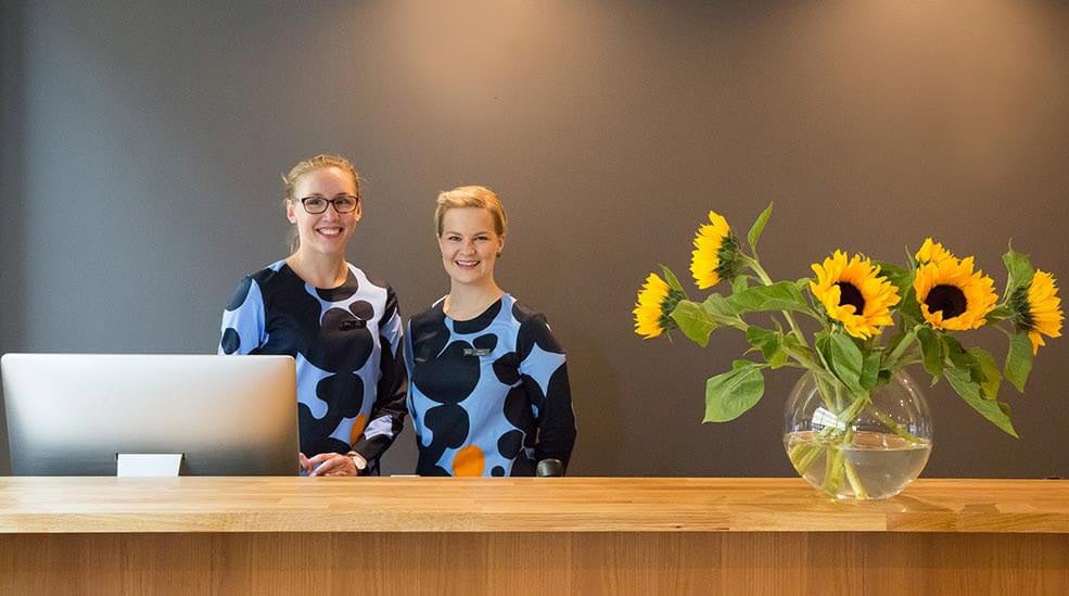 To glade receptionister i lobbyen på Hotel F6 i Helsinki, Finland
