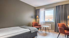 Standard enkeltværelse med seng, orange stole, vindue, lampe og bord hos Quality Hotel Grand Kristianstad