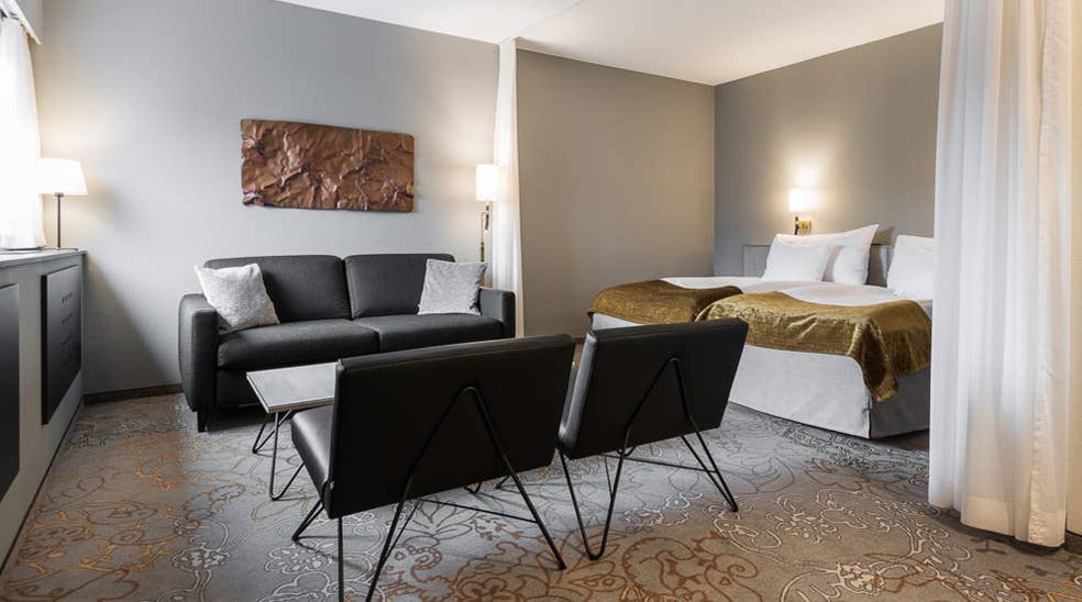 Grå sofa, dobbeltseng og sorte lænestole i Deluxe dobbeltværelse hos Quality Hotel Royal Corner